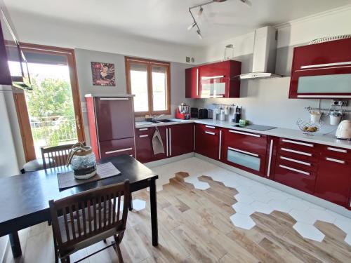 GagnyMaison 190m2 - Entre Paris et Disneyland的厨房配有红色橱柜和桌椅