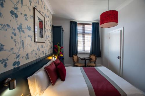 布莱顿霍夫新斯坦住宿加早餐酒店的一间卧室配有一张带红色枕头的大床