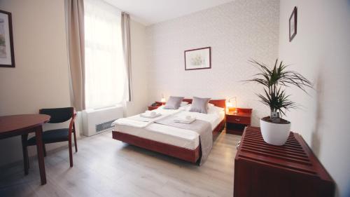 埃格尔Aqua Villa Eger的一间卧室配有一张床和一张带盆栽的桌子