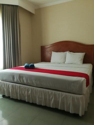 PaalmerahHotel Formosa Jambi的一间卧室配有一张大床和木制床头板