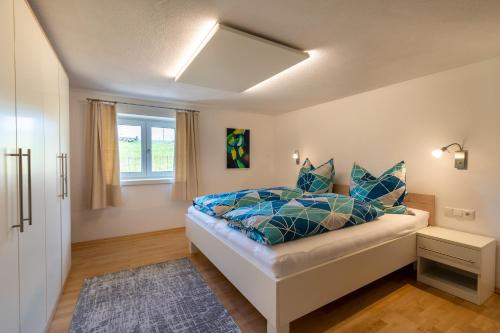 奥夫特尔施旺Ferienwohnung "Florin"的一间卧室配有一张带蓝色枕头的床和一扇窗户。