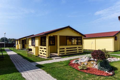 斯文托伊Nameliai Gulbės takas的一座黄色的小房子,前面有一个花园