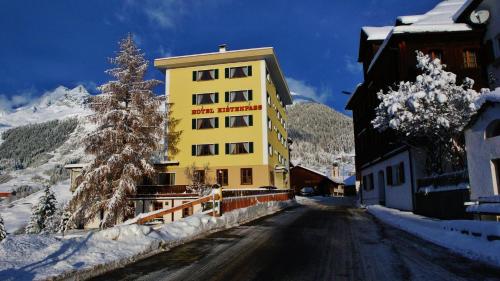 布赖尔齐斯腾帕斯酒店的一条雪覆盖的街道边的黄色建筑