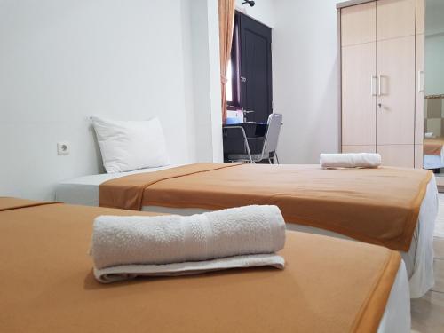 KudusVilletta House Syariah的两张位于酒店客房的床,配有桌子上的毛巾