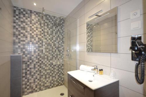 布里昂松艾德维斯酒店的浴室配有盥洗盆和带镜子的淋浴