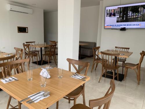 巴耶杜帕尔Hotel Metropolitano Plaza的餐厅设有木桌、椅子和平面电视。