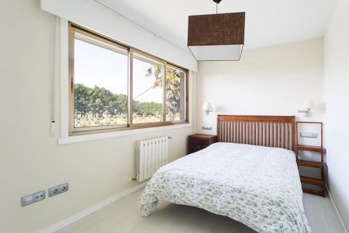 米尼奥Housingcoruña Apartamento Playa Miño 03的白色的卧室设有床和窗户