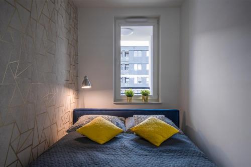 弗罗茨瓦夫Star4You II Apartments的一间卧室配有一张带黄色枕头的床和一扇窗户