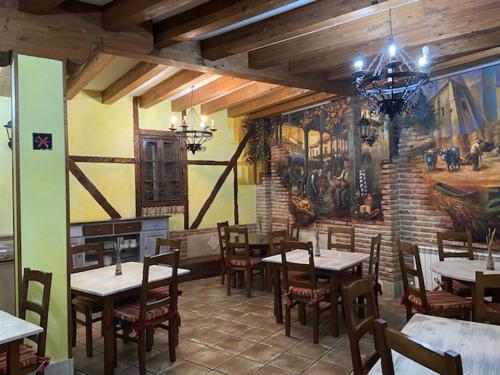 SaldañaHotel Rural El Marqués的一间带桌椅和壁画的餐厅