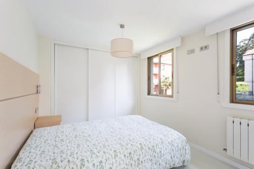 米尼奥Housingcoruña Apartamento Playa Miño 04的一间白色卧室,配有床和2个窗户