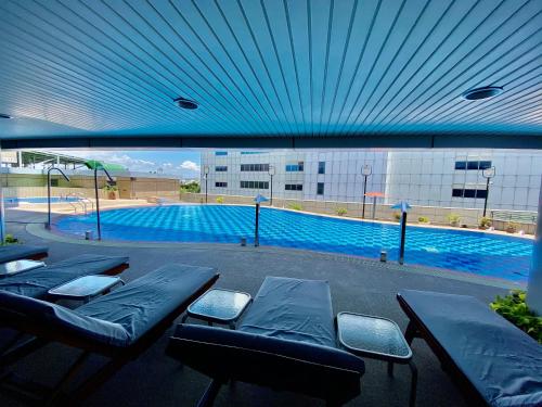 台南台糖长荣酒店 - 台南 的大楼前的游泳池设有蓝色天花板和长凳