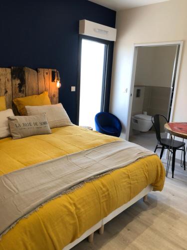 勒克罗图瓦Escale beauté le Crotoy的一间卧室配有一张黄色的大床和一张桌子