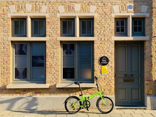 伊普尔Gîte de Lombard的停在砖砌建筑前面的绿色自行车