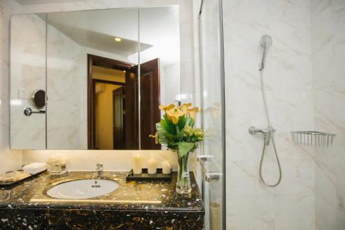 海口海口湾恒大逸阁度假公寓的浴室配有盥洗盆和带镜子的淋浴