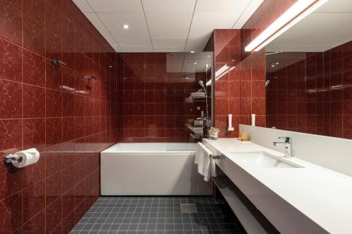 塔尔图塔尔图艺术帕拉斯酒店的浴室设有水槽、浴缸和红色瓷砖。