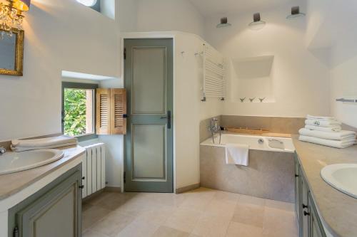 博尼约La Ferme du Haut Trigaud的浴室配有2个盥洗盆、浴缸和淋浴。