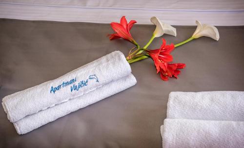 蒂瓦特Apartments Vujicic的床上有一条毛巾和一朵花