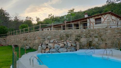 哈兰迪雅·德·拉·维尔Hotel Rural San Giles的一座大型游泳池,毗邻石墙