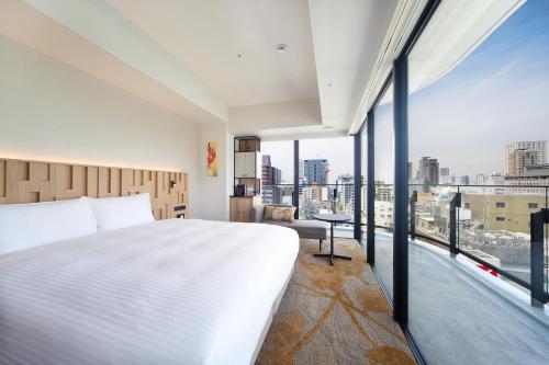 大阪Miyako City Osaka Hommachi的卧室设有白色的床和大窗户