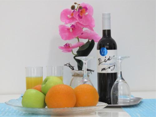 克勒克Apartmani Villa Delija Klek的水果盘,一瓶葡萄酒和鲜花