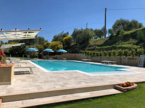 渥尔特拉Agriturismo Casale Giulia的一个带遮阳伞的庭院内的游泳池