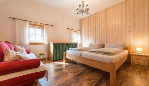 格伦德尔湖Das Haus am Grundlsee的一间卧室配有两张床和一张红色沙发