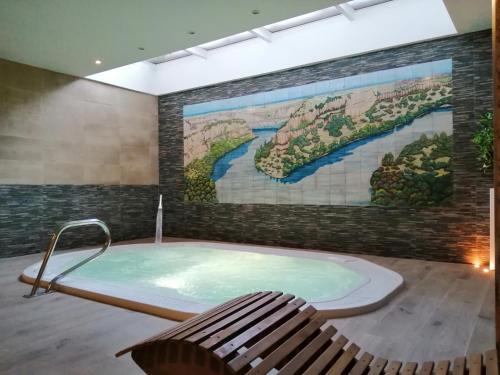 塞普尔韦达Hotel Rural & SPA Puente del Duratón的壁画客房内的按摩浴缸