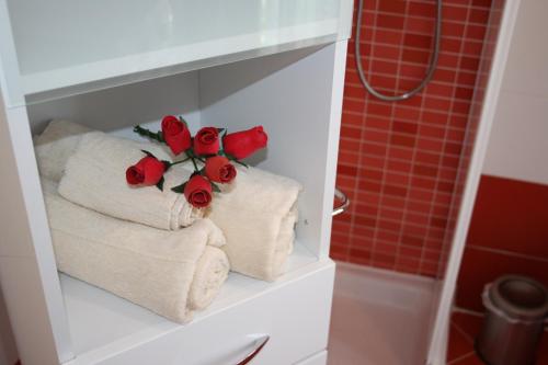 卡尔达诺阿尔坎波Le Margherite的浴室的架子上摆放着毛巾和玫瑰