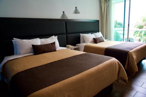 乔卢拉Hotel Posada Señorial的配有窗户的酒店客房内的两张床