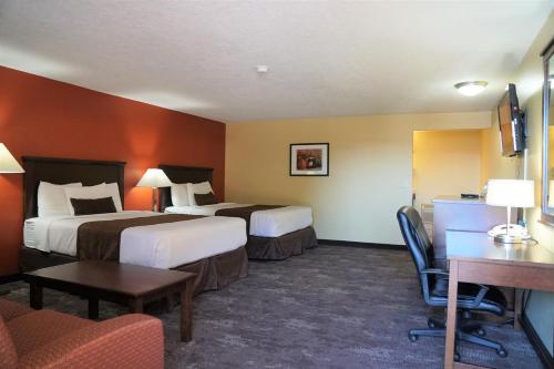 麦克明维尔麦克明维尔汽车旅馆的酒店客房带两张床和一张桌子以及椅子。