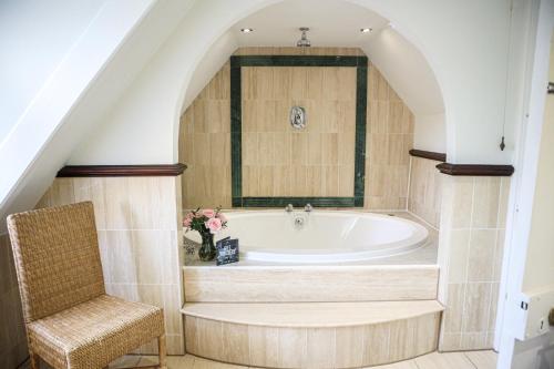 霍利Langshott Manor - Luxury Hotel Gatwick的带浴缸和椅子的浴室