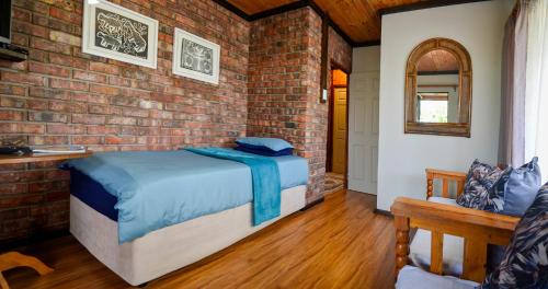 科尔切斯特Palm Cottage - Colchester - 5km from Elephant Park的一间卧室设有一张床和砖墙