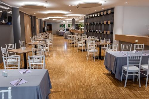 萨格勒布学术酒店的用餐室配有桌子和白色椅子
