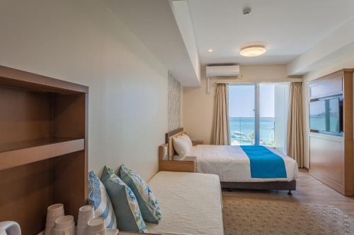 名户Kariyushi LCH. Resort的一间卧室配有一张床,享有海景