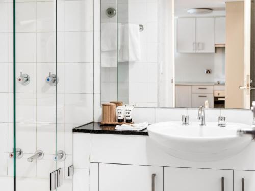悉尼快斯特曼利酒店的白色的浴室设有水槽和淋浴。