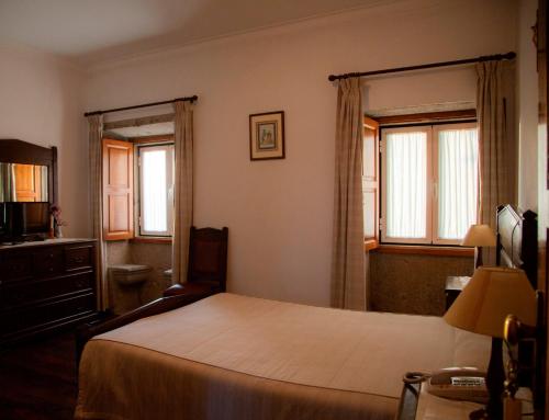 普拉多Quinta de São Bento的一间卧室设有一张大床和两个窗户。