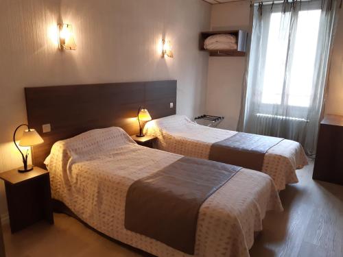 马扎梅Logis Hotels - Hôtel Le Boulevard的酒店客房设有两张床和两盏灯。