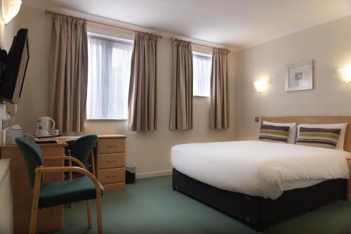 斯托克波特威克利夫酒店的一间卧室配有一张床、一张桌子和一把椅子