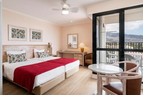丰沙尔Buganvilia Studio Hotel的一间卧室配有一张床、一张桌子和一个窗户。