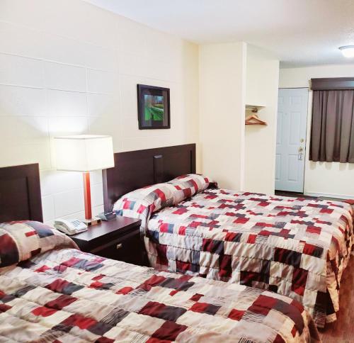 大草原城加拿大汽车旅馆的酒店客房设有两张床和一张带台灯的桌子。