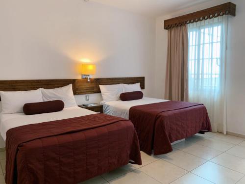 乌鲁阿潘HOTEL MI SOLAR EJECUTIVO的酒店客房设有两张床和窗户。