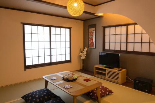 KitagatamachiSyukuyaYokohama Main Building 2F - Vacation STAY 82577的客厅配有桌子和电视