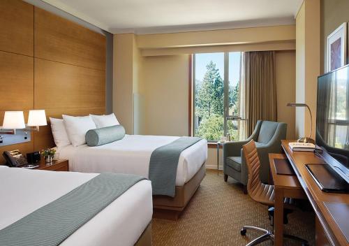 洛杉矶Luskin Hotel的酒店客房设有两张床、一张桌子和一台电视。