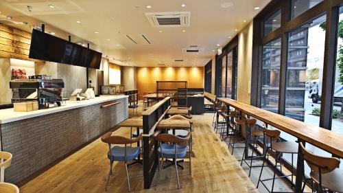 大阪Welina Hotel Premier Nakanoshima EAST的餐厅内带木桌椅的酒吧