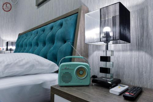 库塔伊西SULIKO Apartment的一间卧室,配有一张睡床,床头柜上挂着蓝色的钟