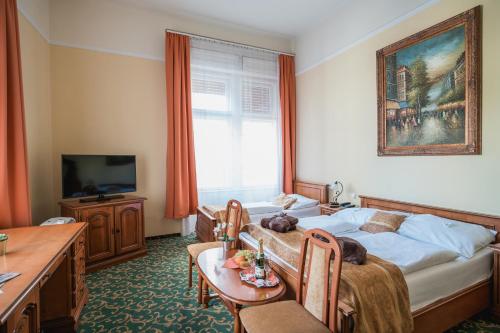 布达佩斯City Hotel UNIO superior的一间卧室配有一张床、一张桌子和一台电视。