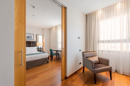 瓦伦西亚欧洲之星瓦伦西亚大酒店的一间卧室配有一张床、一把椅子和镜子