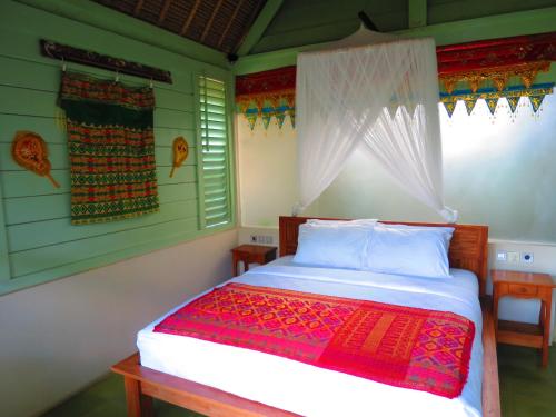甘地达萨曼吉斯花园迪维度假酒店的一间卧室配有一张床铺,床上铺有红色毯子