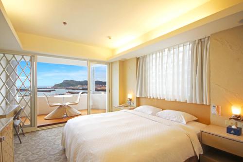 基隆蔚蓝海景旅店的一间卧室设有一张大床和一个大窗户