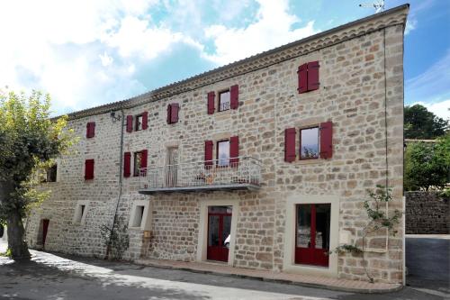 SanilhacChambre Comballe charmante avec jacuzzi的一座带红色窗户和阳台的大型砖砌建筑